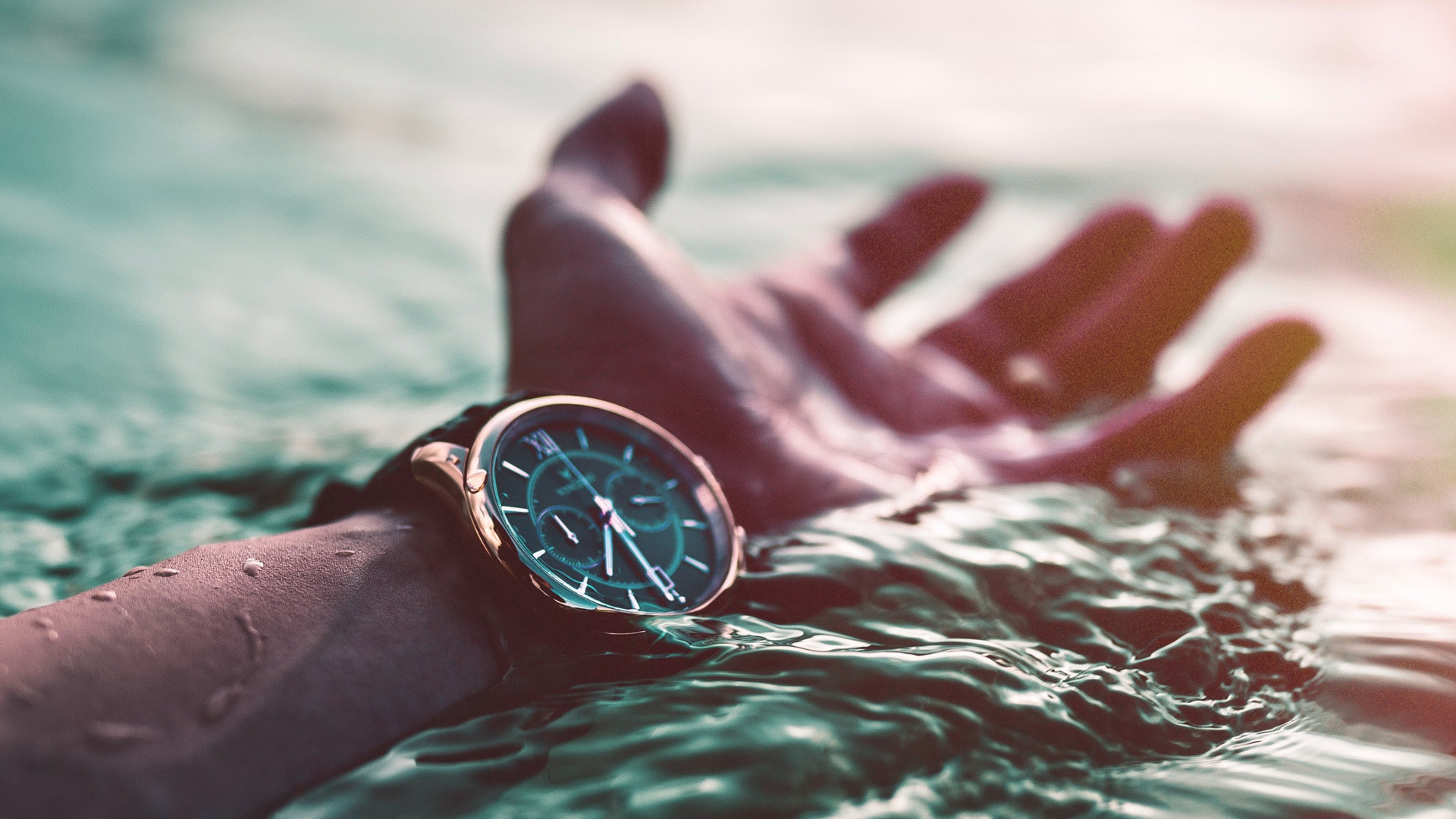 Arm stretched out to help wearing watch in the water (Alex Perez unsplash.com)