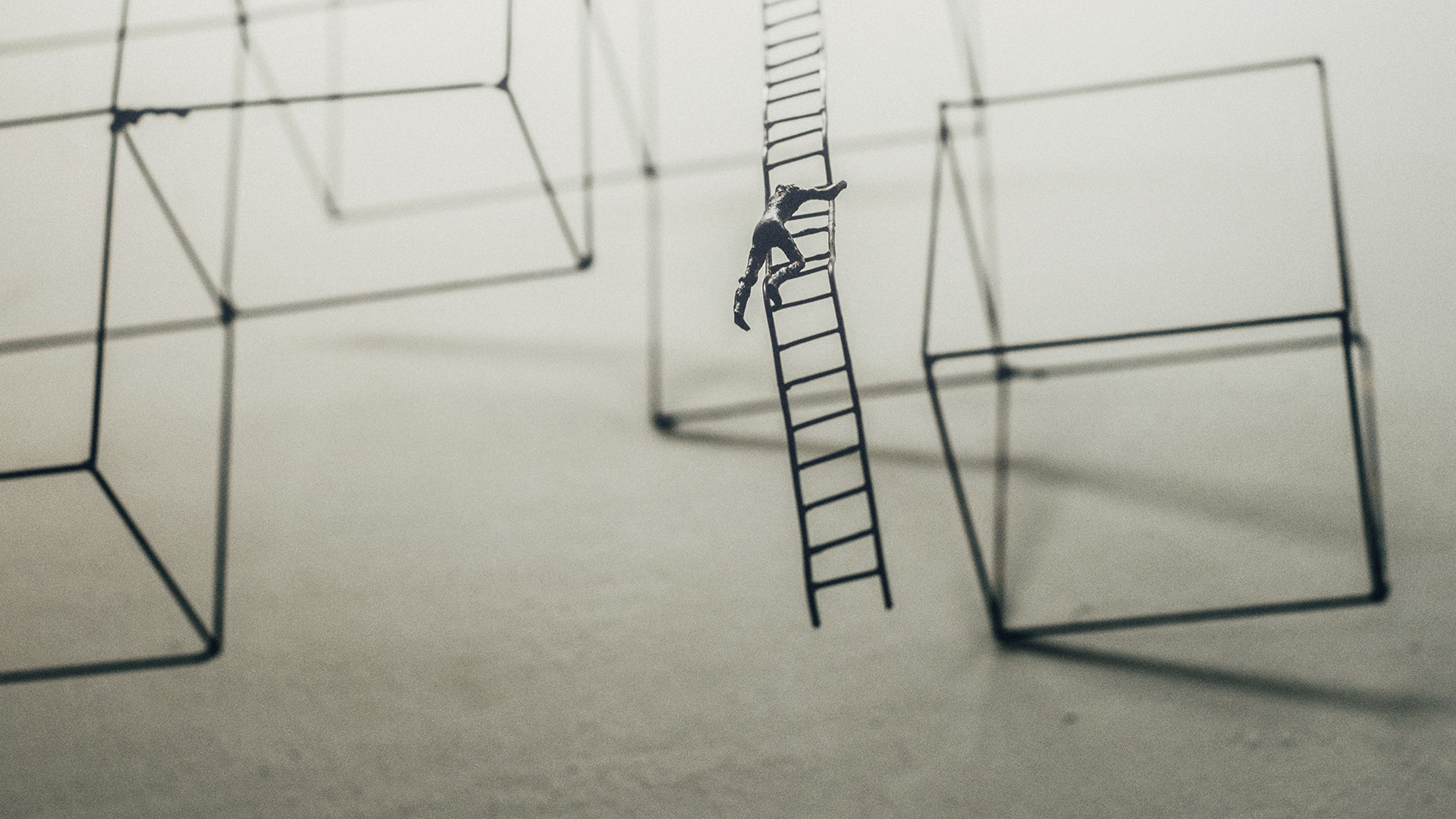 Metal framework art depicting man climbing a suspended ladder (Jason Wong - unsplash.com)