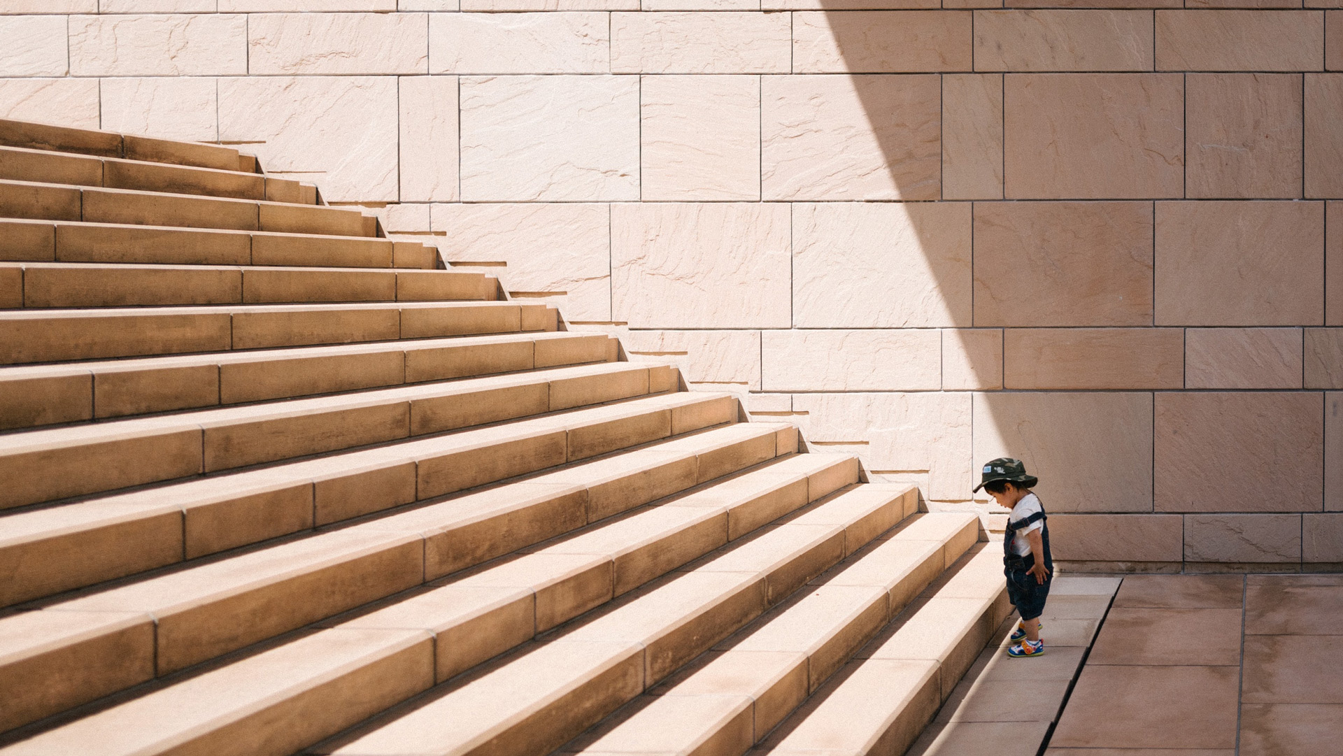 Young boy standing at the beginning of stairs, looking down at the first step (Jukan Tateisi- Unsplash.com)